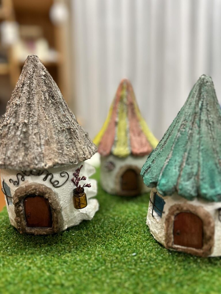 芝生の上に並べられた小さな家型のミニチュア雑貨オブジェのクローズアップ