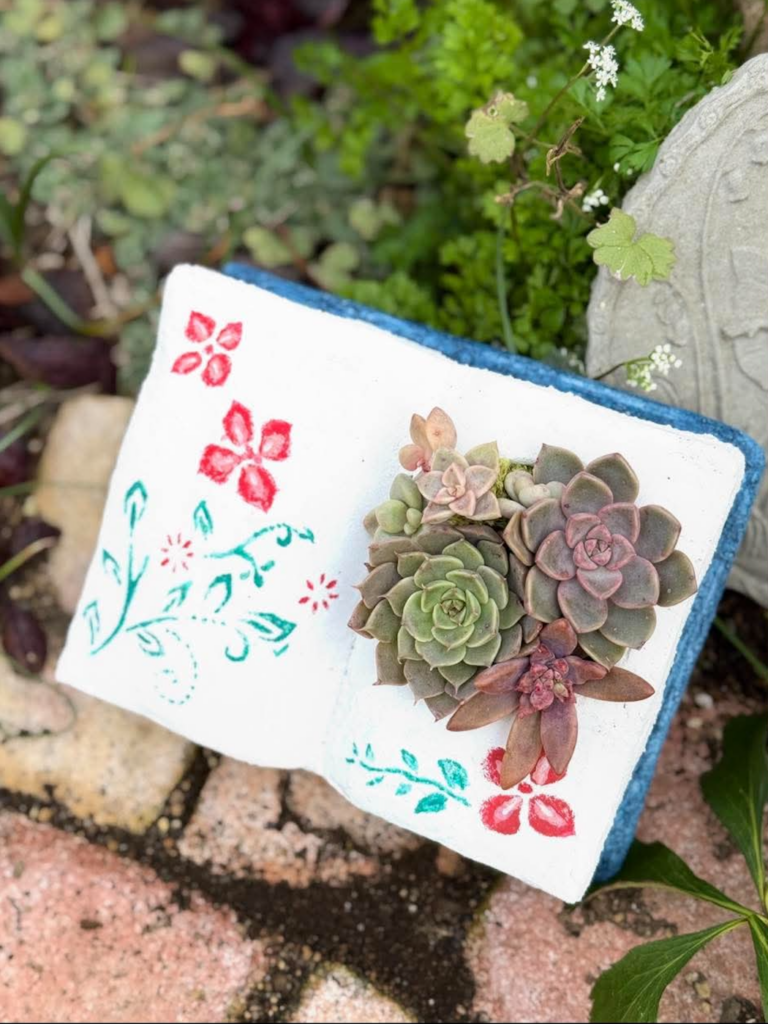 白い鉢に花柄の装飾と多肉植物が寄せ植えされたガーデニング作品