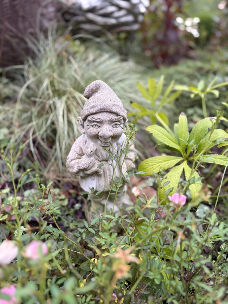 草花の間から顔をのぞかせる小人のガーデンオブジェ