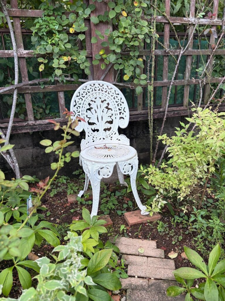 草花に囲まれた庭に置かれた白いガーデンチェア