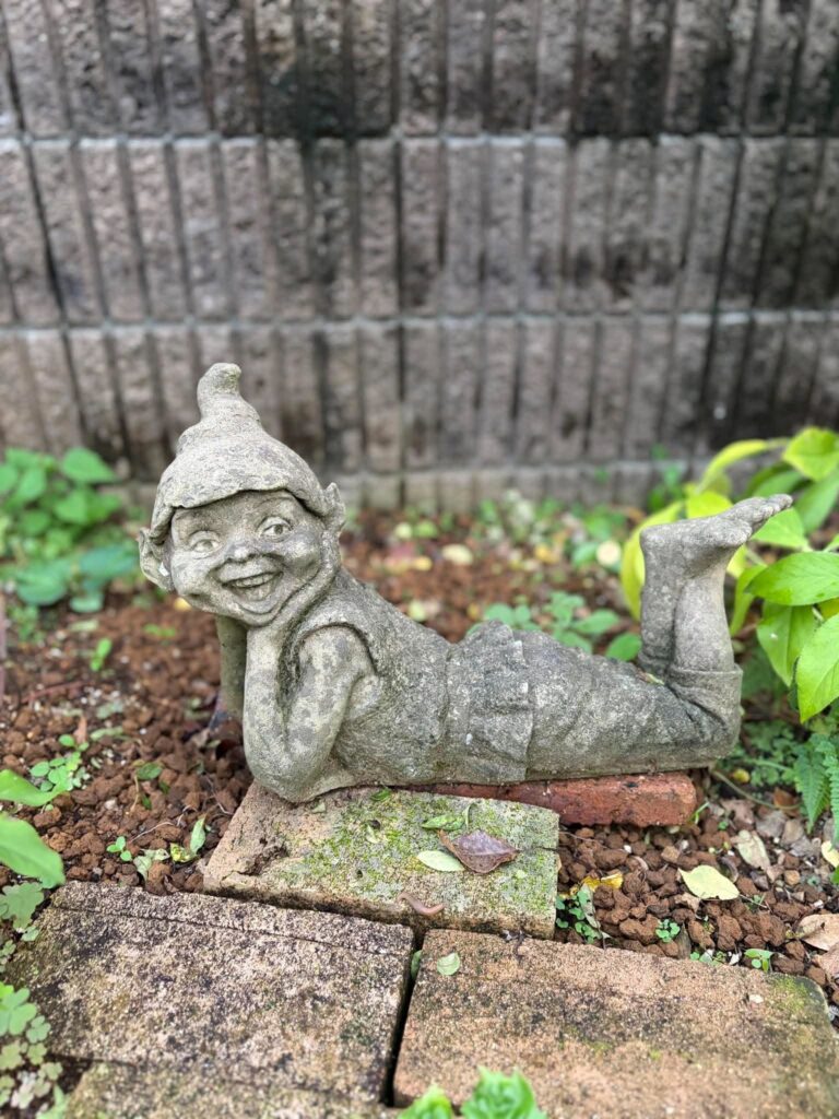 庭の片隅で頬杖をついて寝転ぶ小人のガーデンオブジェ